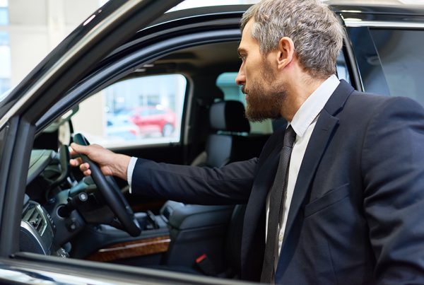 A car salesman inspects the inside of a vehicle.