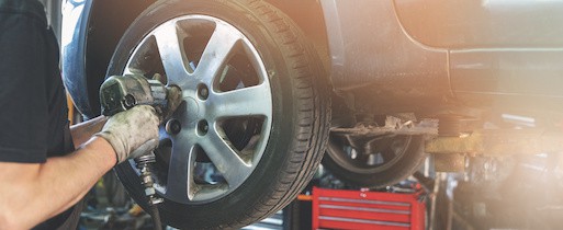 A car mechanic is shown screwing the wheel at auto repair garage